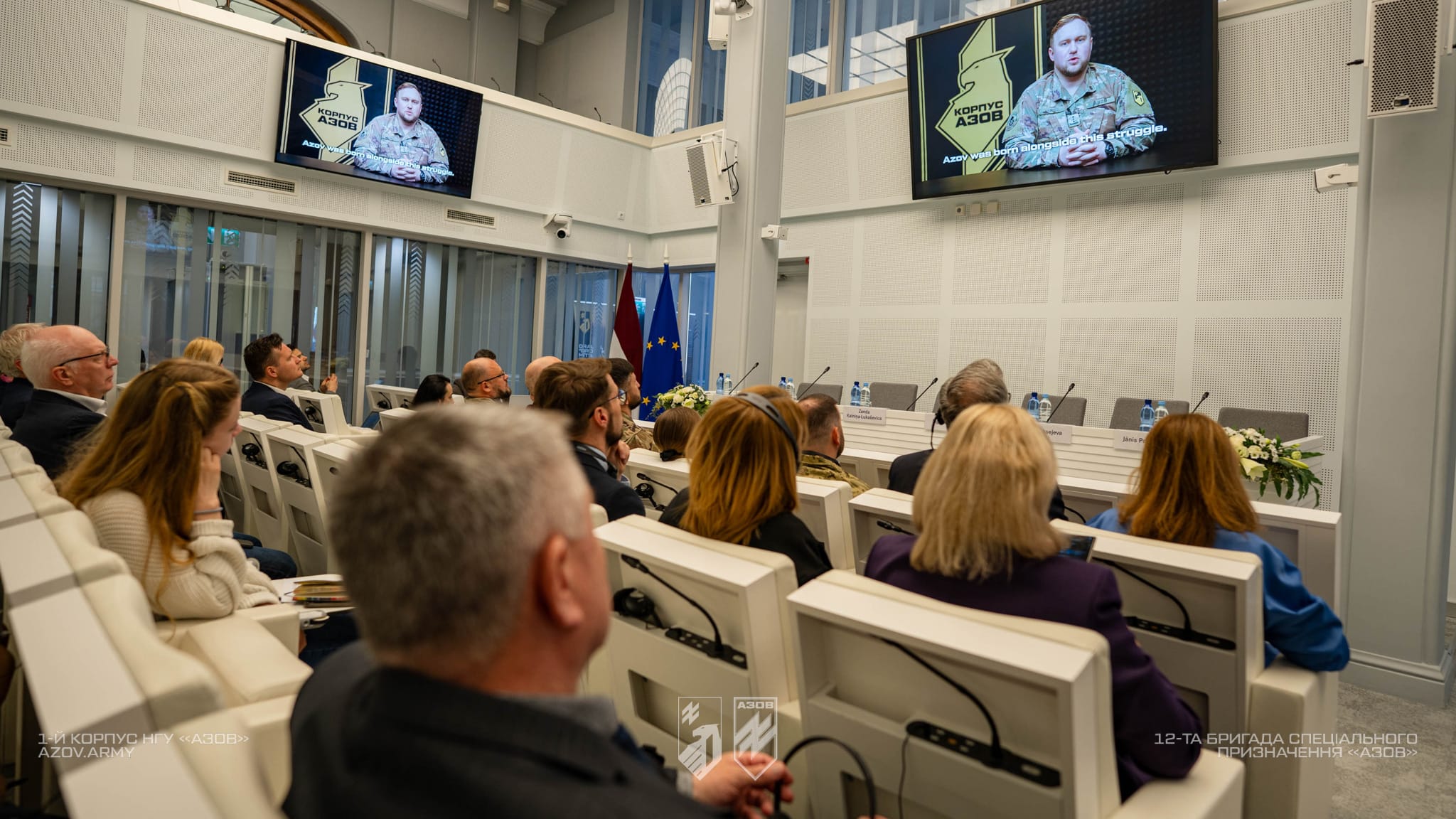 Делегація та учасники заходу переглядають презентацію 1-го корпусу НГУ «Азов» у конференц-залі в Латвії